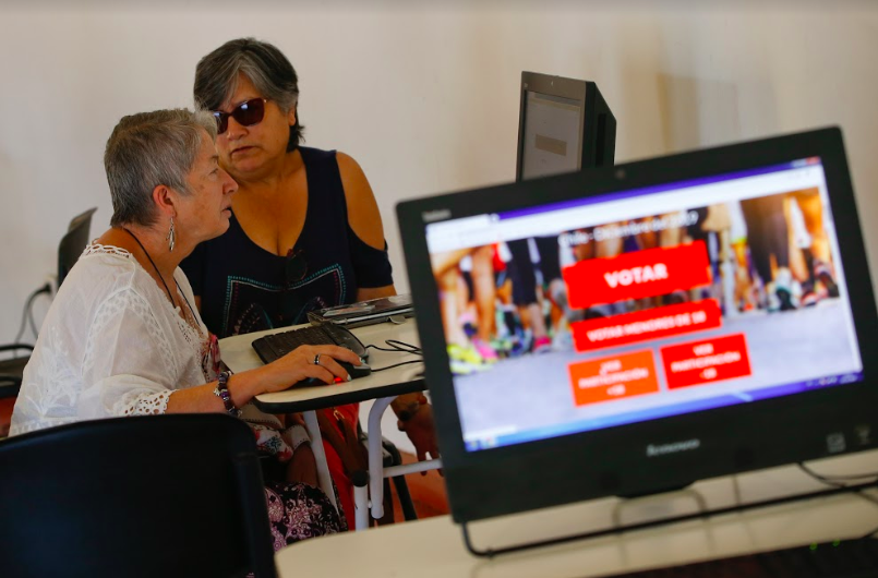 Two women voting electronically and a computer screen with the EVoting voting platform